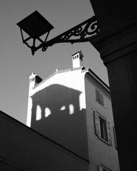 Artistic black and white photo of building with dramatic shadows, emphasizing architectural details.