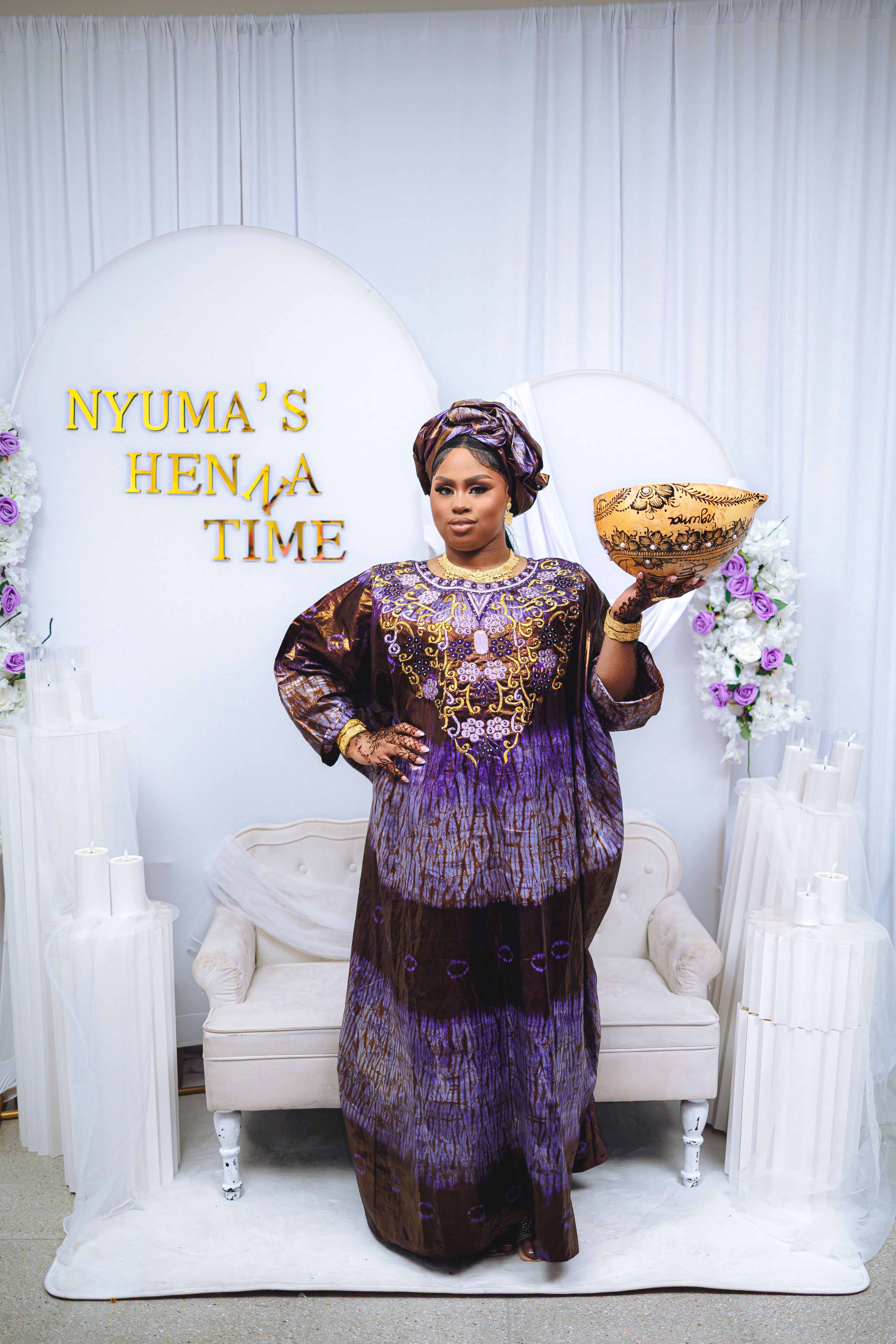 Woman in traditional attire holding a decorated bowl at a henna ceremony.