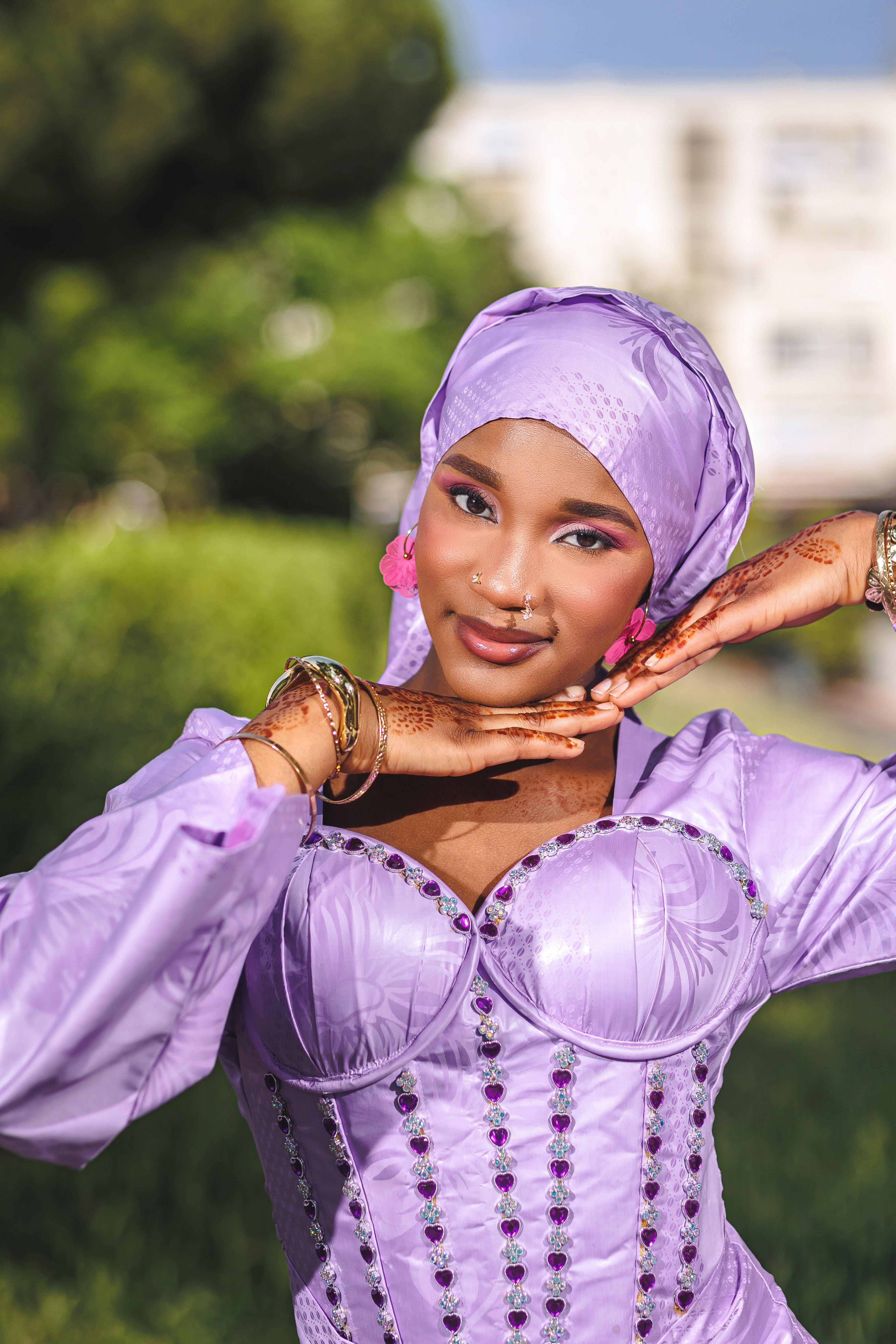 Beautiful woman posing outdoors in a lavender dress, exuding confidence and elegance.