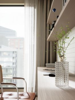 Light-filled home office with a modern design, featuring a glass vase and wooden elements.