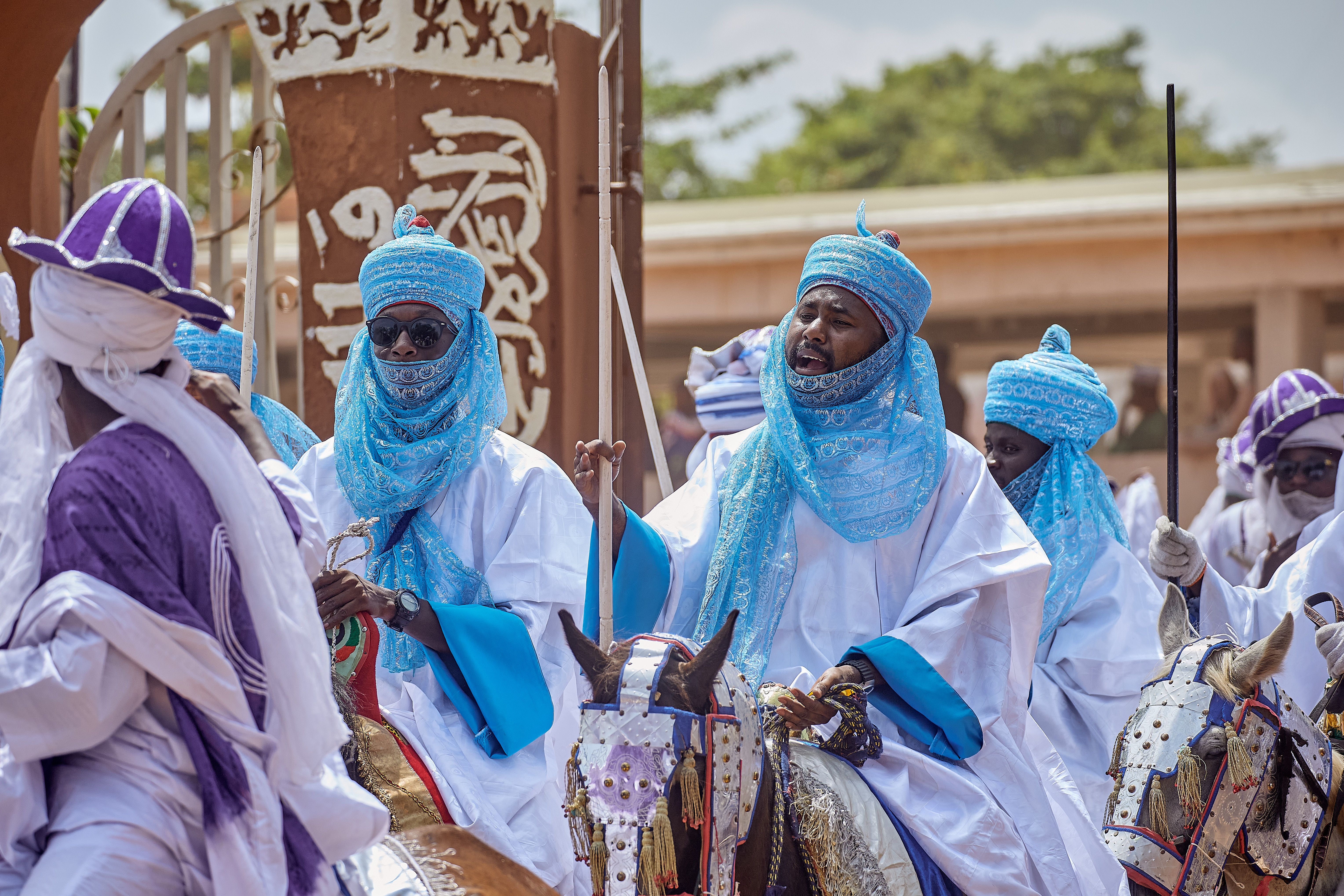 Colorful scene of Nigerian horsemen in traditional attire at a cultural festival.
