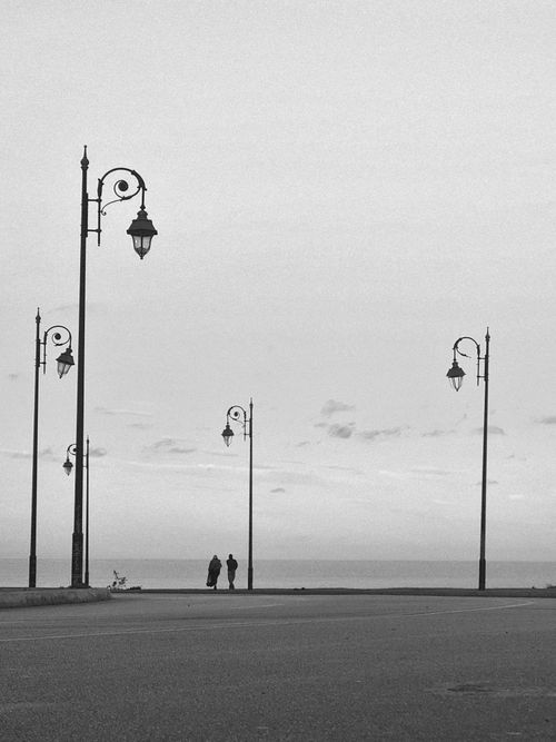 Free Minimalist black and white photo of a seaside street with street lamps in Morocco. Stock Photo