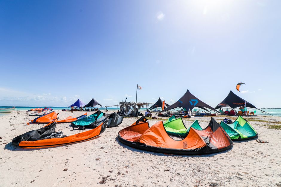 Colorful kites and gear on a pristine Caribbean beach, ideal for kiteboarding enthusiasts.