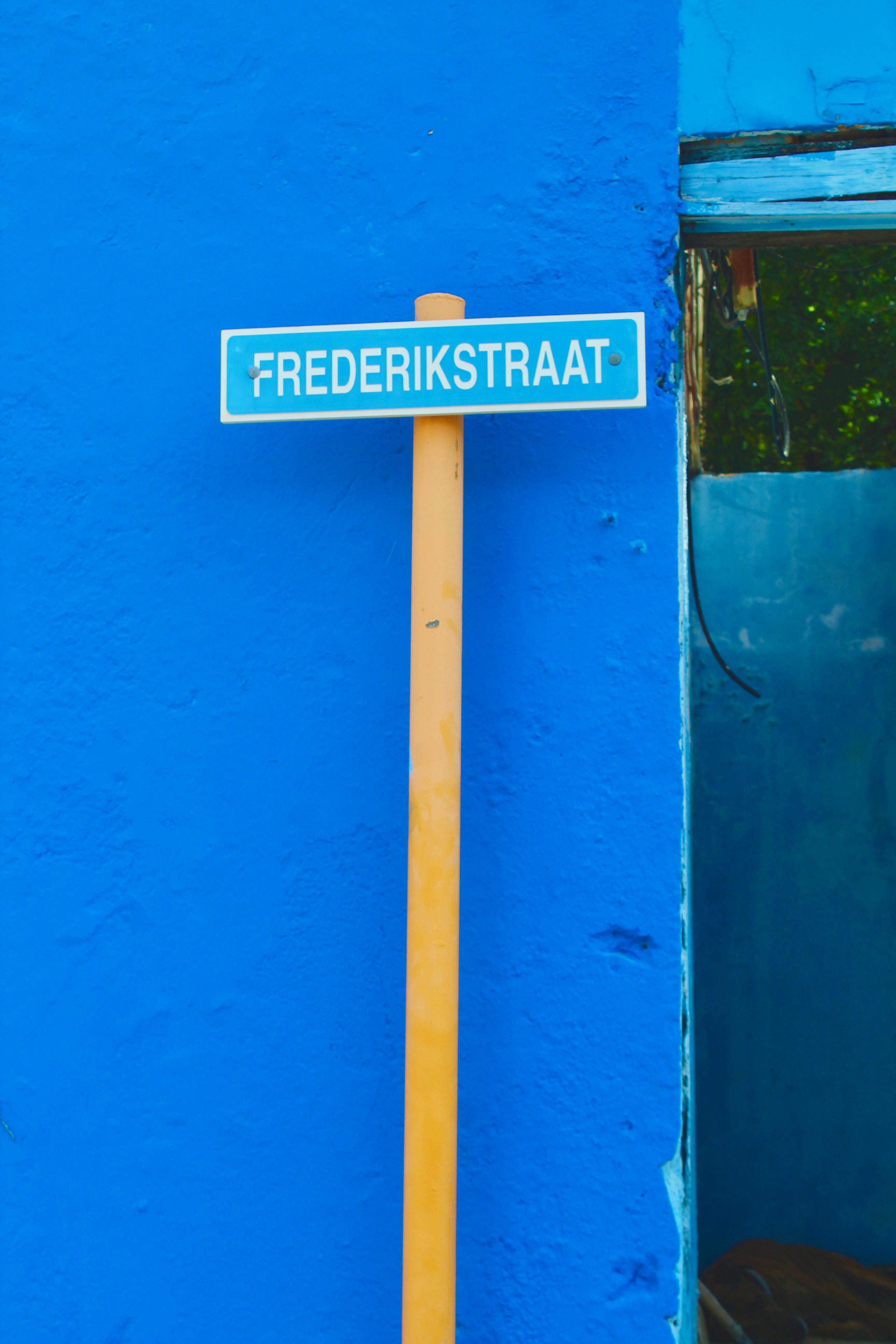 Street sign of Frederikstraat on a vivid blue wall in Willemstad, Curaçao, showcasing local architecture.