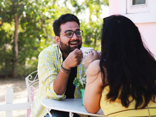 Free A happy couple sharing coffee and laughter outdoors, capturing love and summertime vibes. Stock Photo