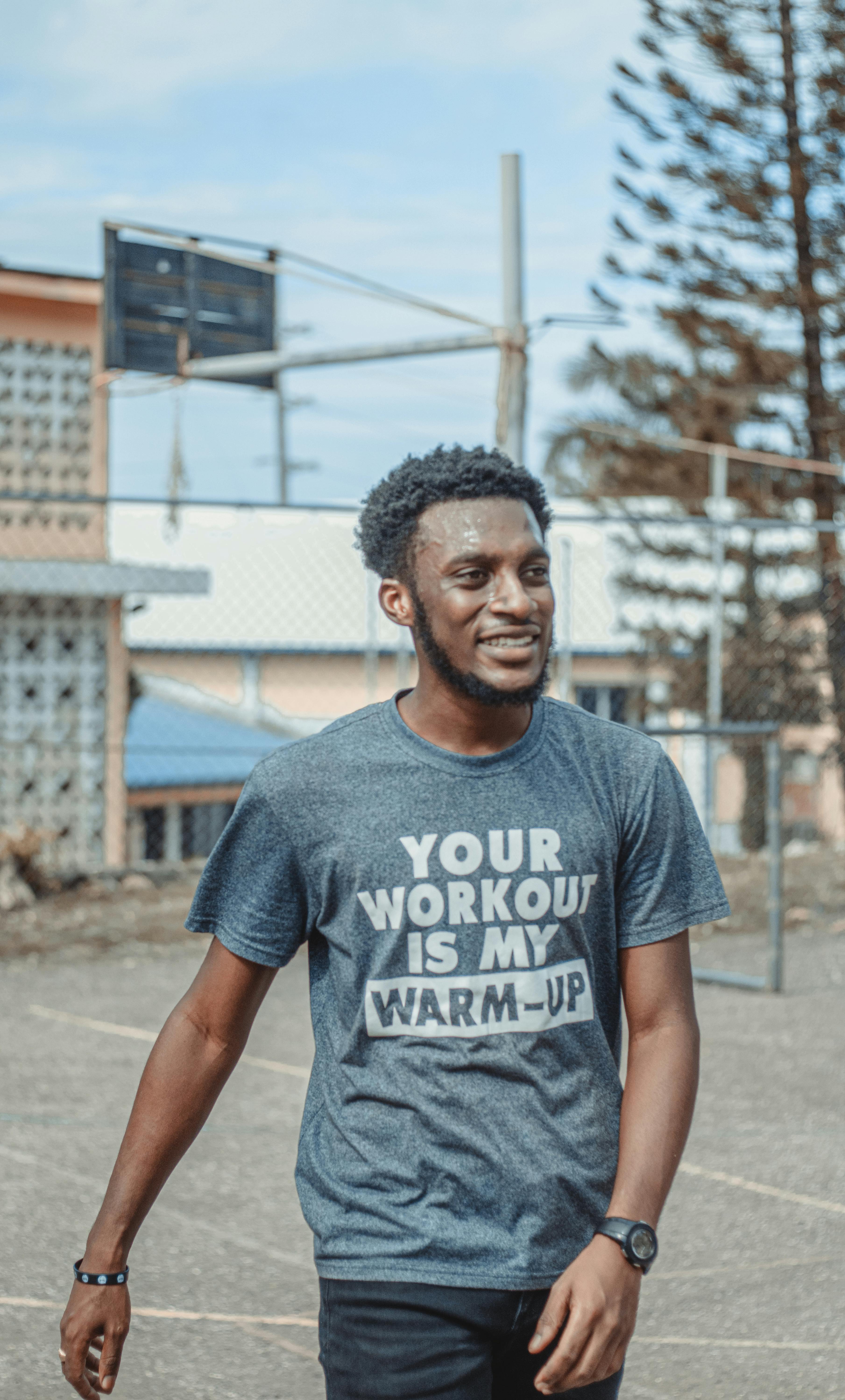 man in gray crew neck t shirt standing on gray concrete pavement