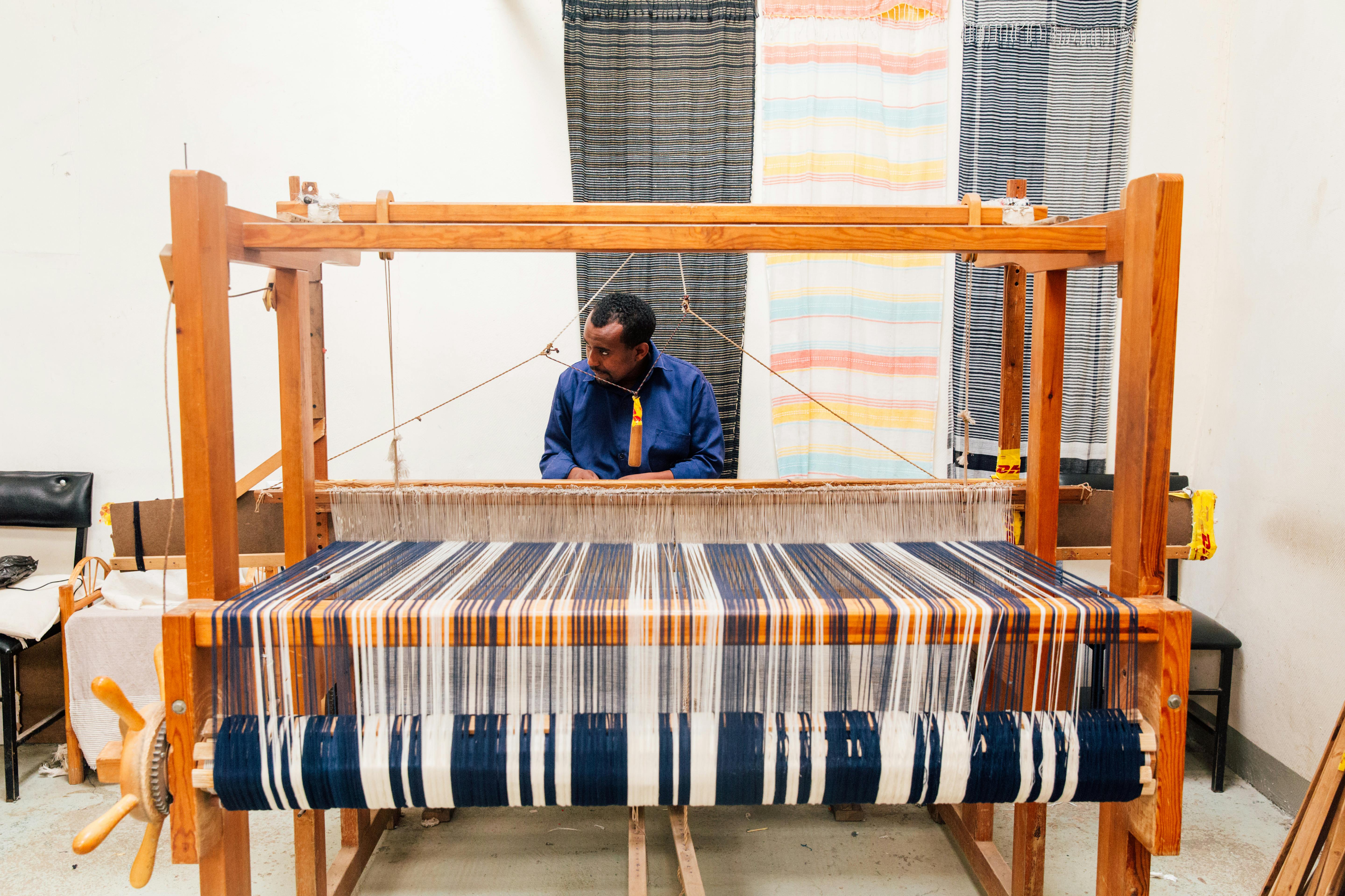 ethnic craftsman working on loom in workshop