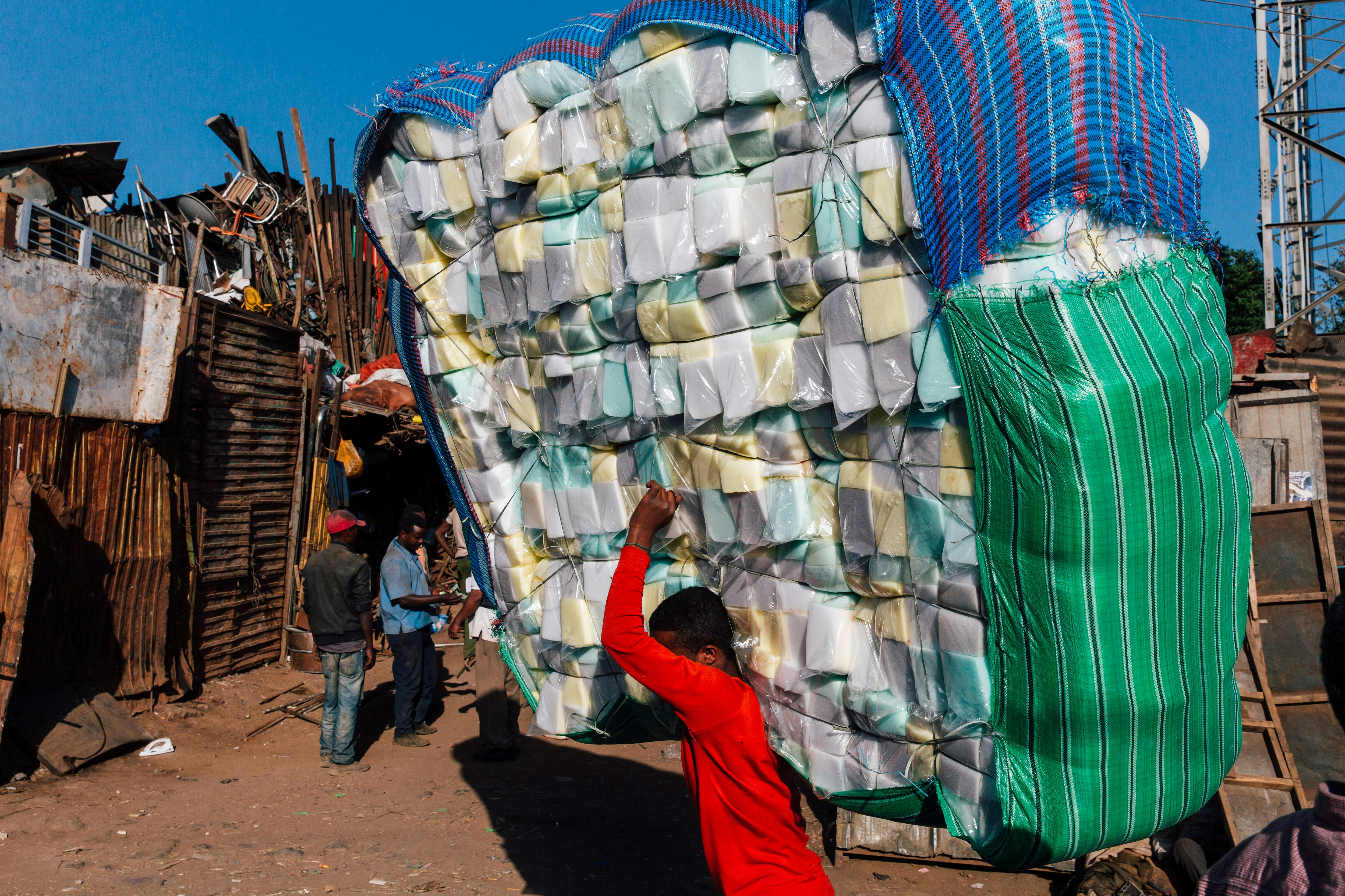 unrecognizable ethnic teenager carrying pile of goods on street