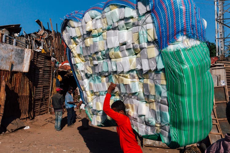 Unrecognizable Ethnic Teenager Carrying Pile Of Goods On Street