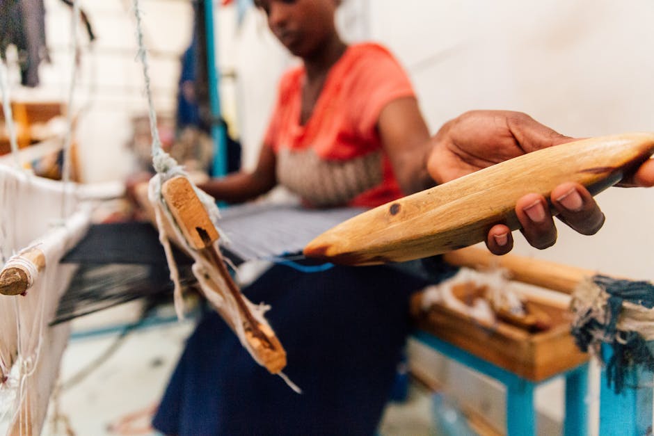 Focused African woman weaving cloth on a traditional loom in a studio setting.
