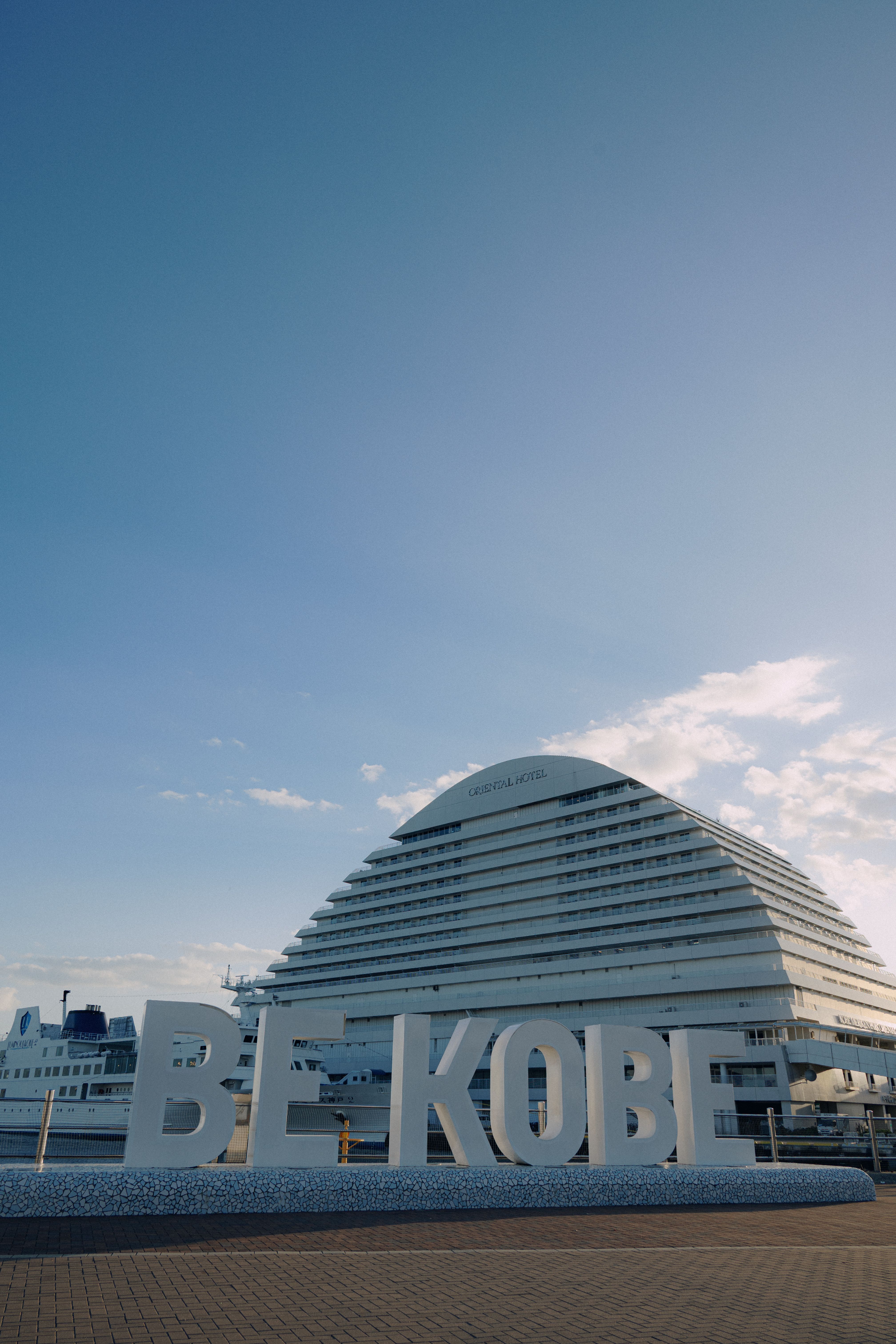 View of the BE KOBE sign with the iconic Meriken Park hotel in Kobe, Japan.