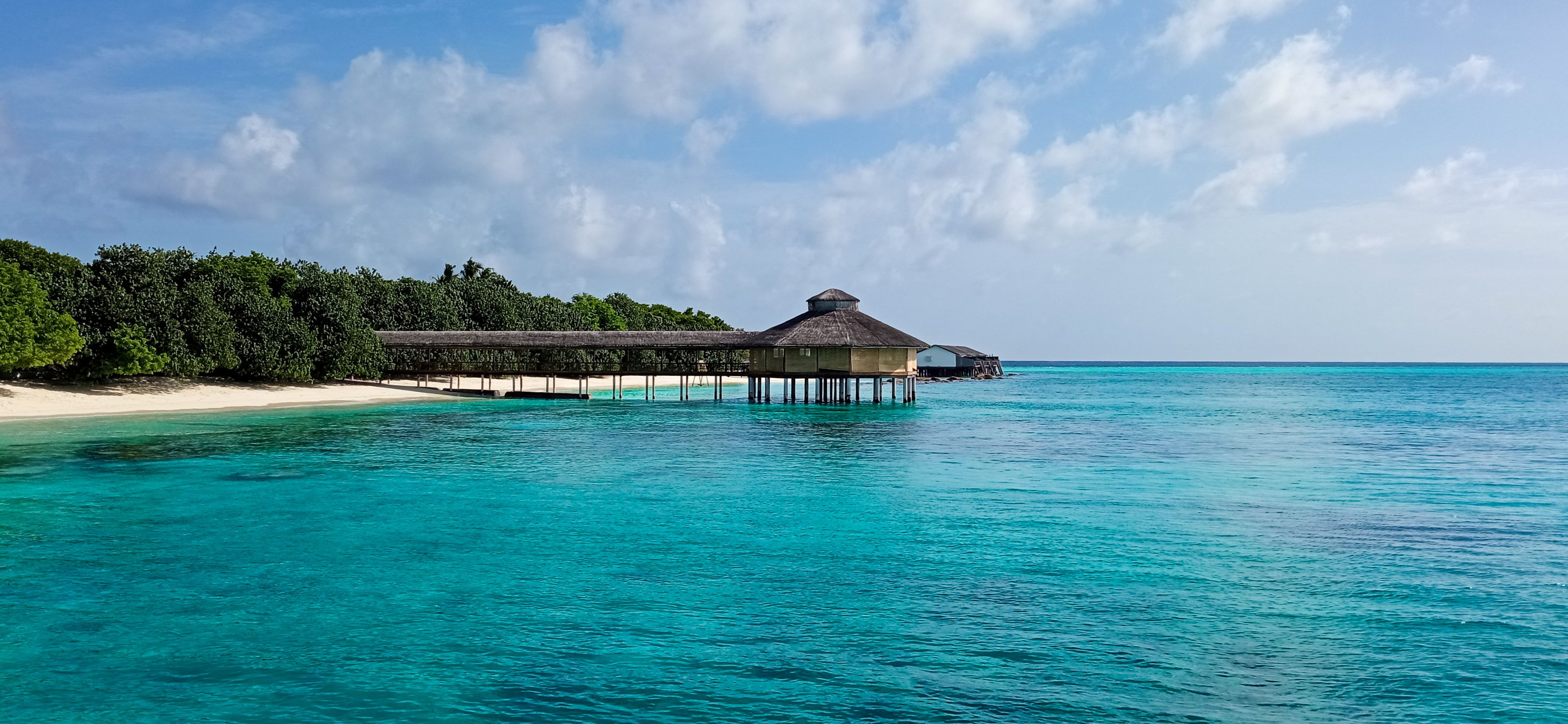 A serene tropical resort with overwater bungalows and turquoise waters under a clear sky.