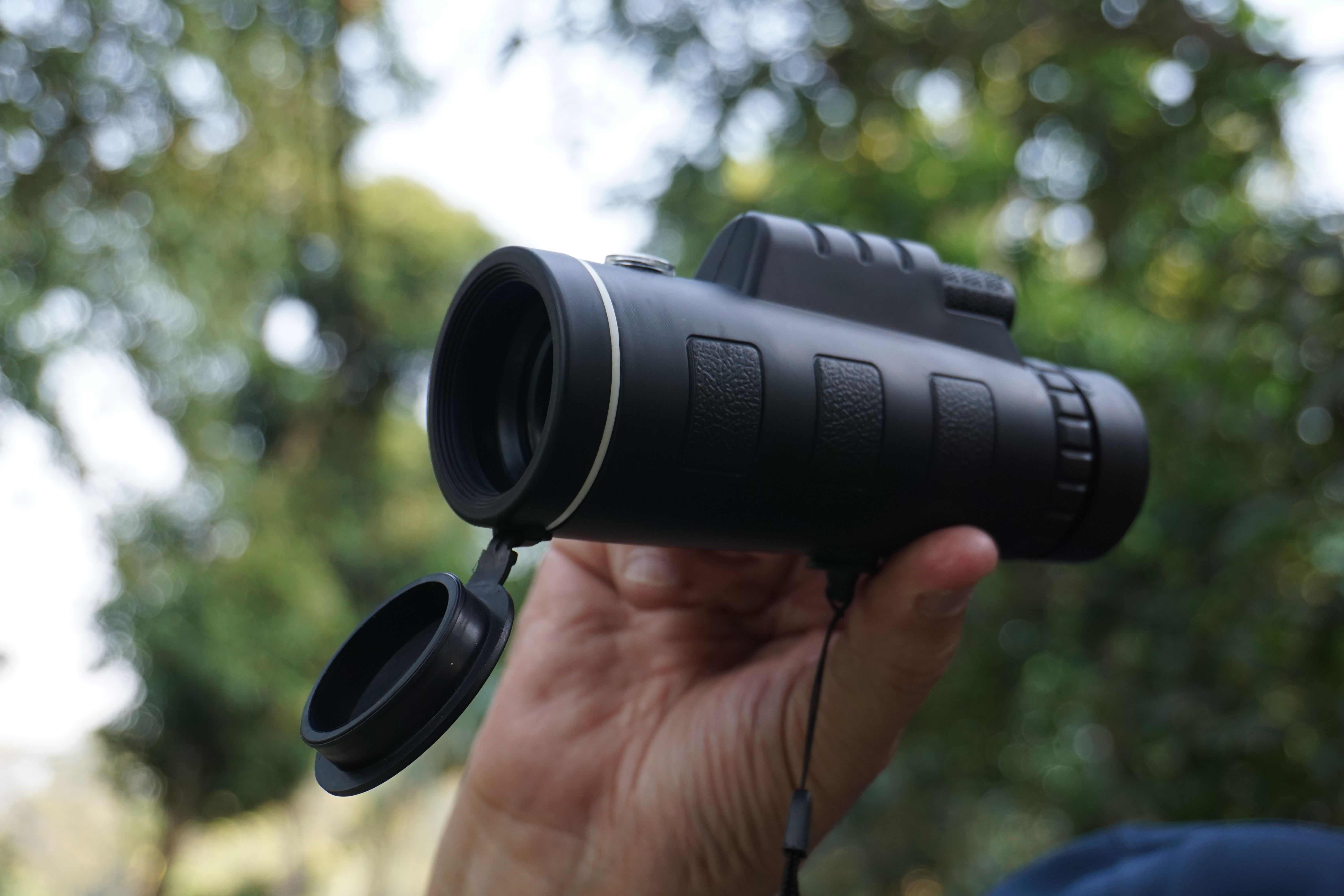 Hand holding binoculars in an outdoor setting, perfect for bird watching.