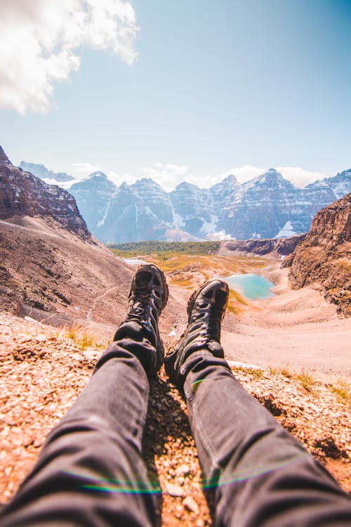 Person in Black Pants and Black Hiking Shoes Sitting on the Ground