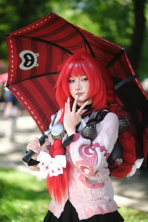Free Cosplayer with red wig and decorative umbrella in an outdoor setting. Stock Photo