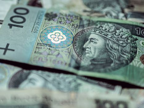 Detailed close-up of Polish zloty banknotes focusing on 100 PLN, highlighting intricate currency design.