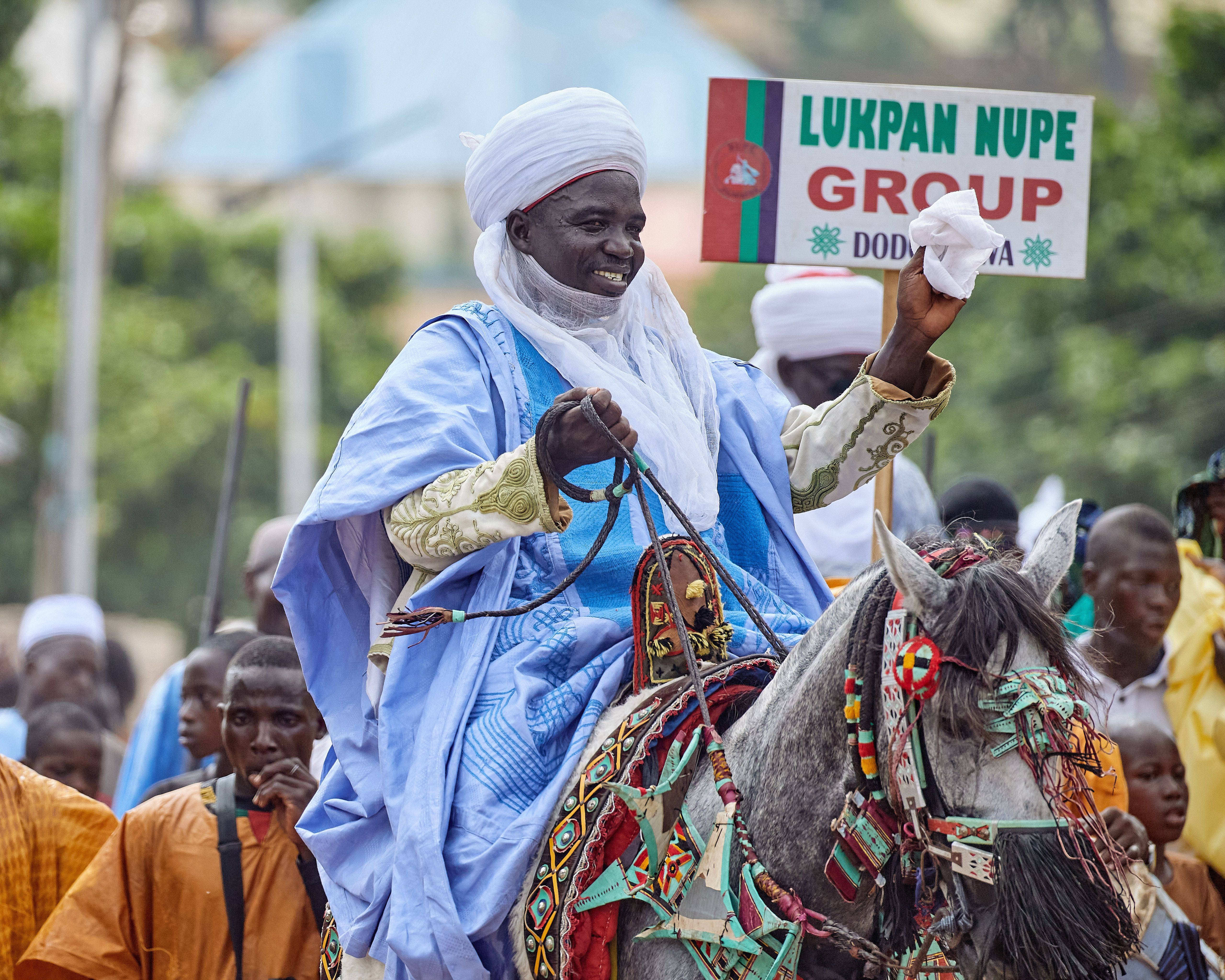 Nigerian festival featuring a man in traditional attire riding a decorated horse.