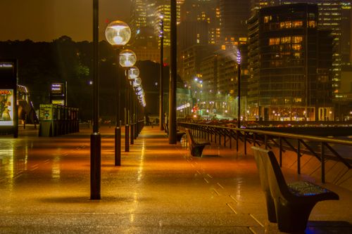 Free Vibrant nighttime scene of Sydney's Opera House promenade, showcasing glowing street lamps and urban architecture. Stock Photo