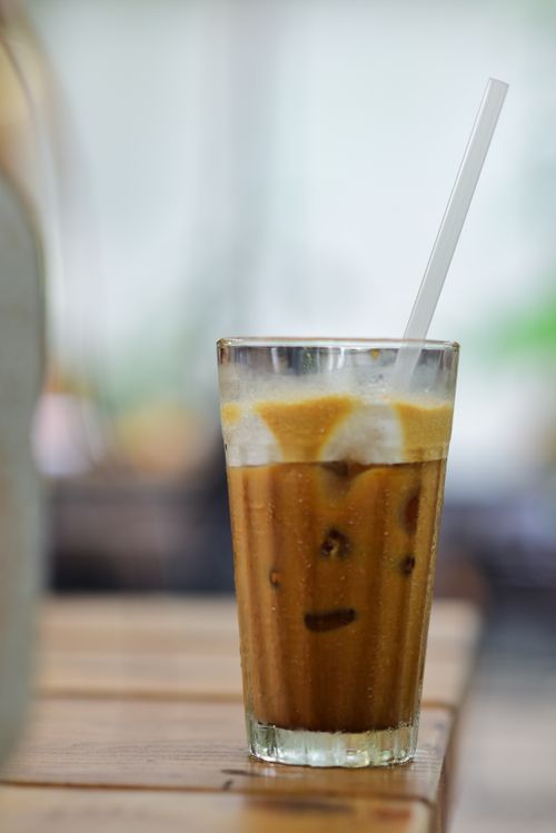 Free A glass of refreshing iced coffee on a wooden table with natural light. Stock Photo