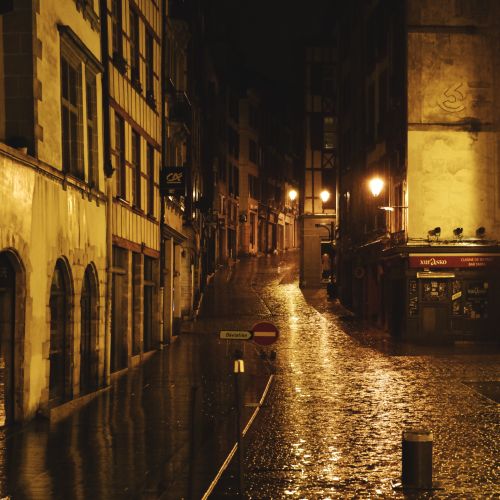 Free Moody cityscape of Bayonne at night, featuring historic architecture and wet cobblestone streets. Stock Photo