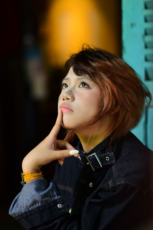 Free Portrait of a young woman in denim, pondering deeply under moody lights. Stock Photo
