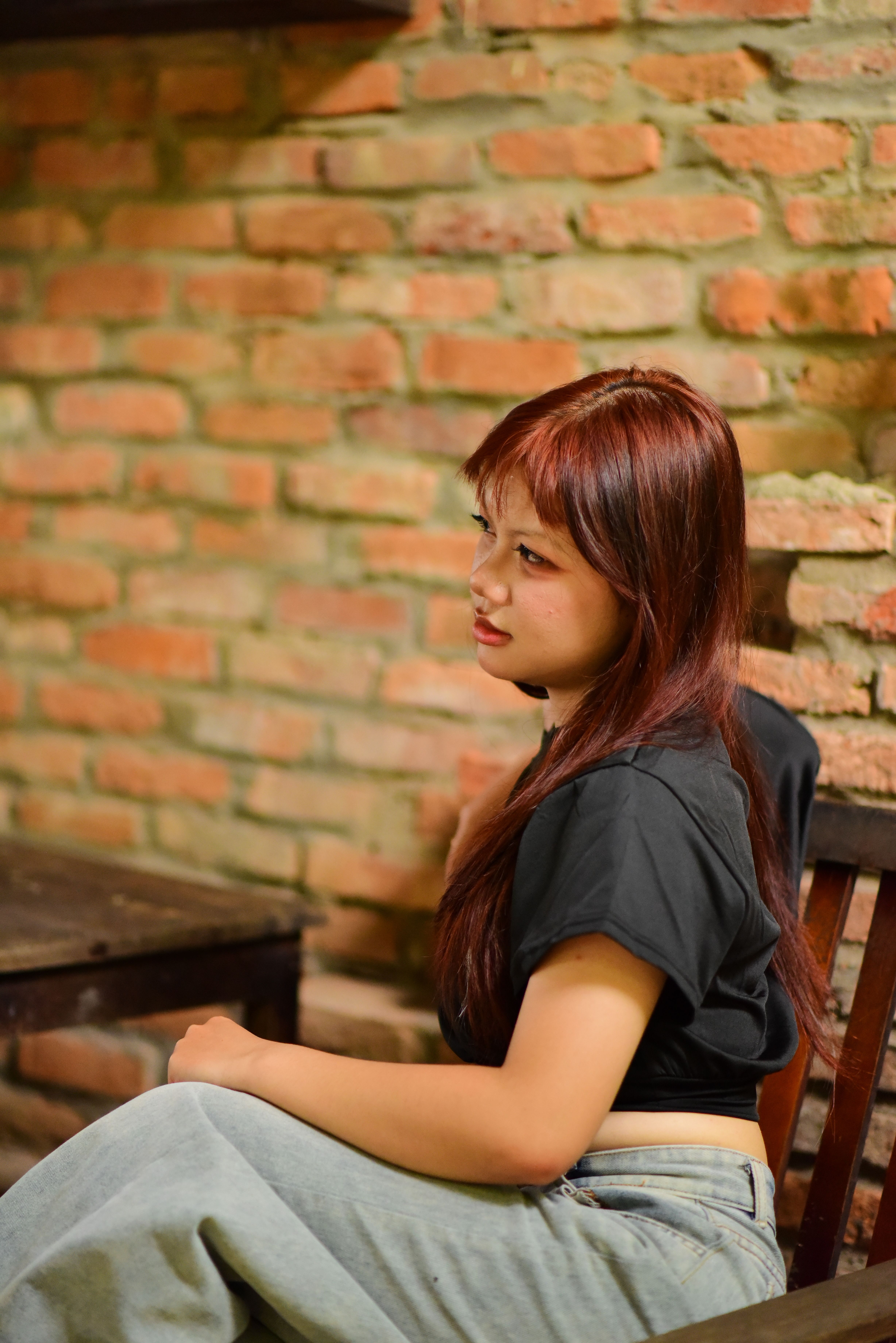 Woman in Casual Outfit Sitting Against Brick Wall
