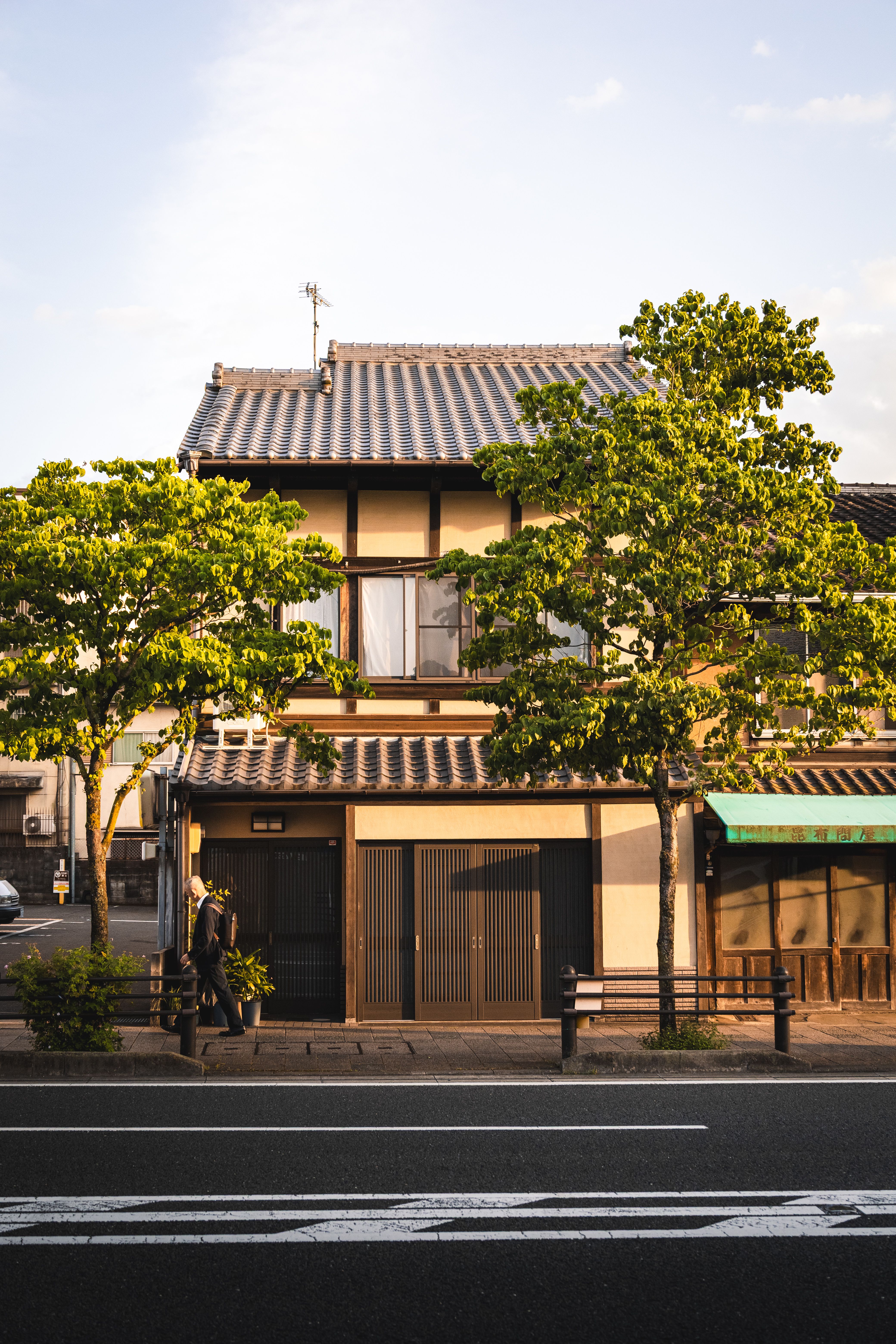 Charming traditional Japanese house with trees lining a quiet street at sunset.