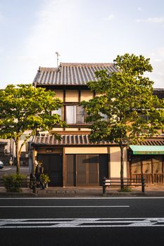 Charming traditional Japanese house with trees lining a quiet street at sunset.
