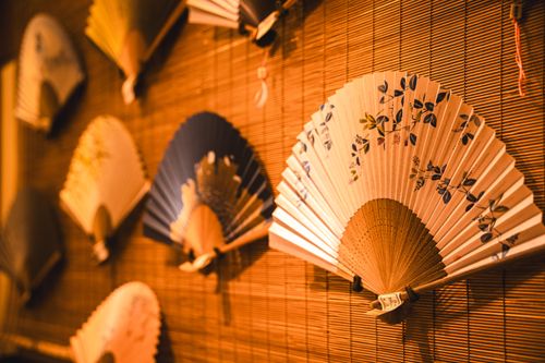 Folding paper fans displayed on a bamboo screen — photo by Ali Arapoglu on Pexels