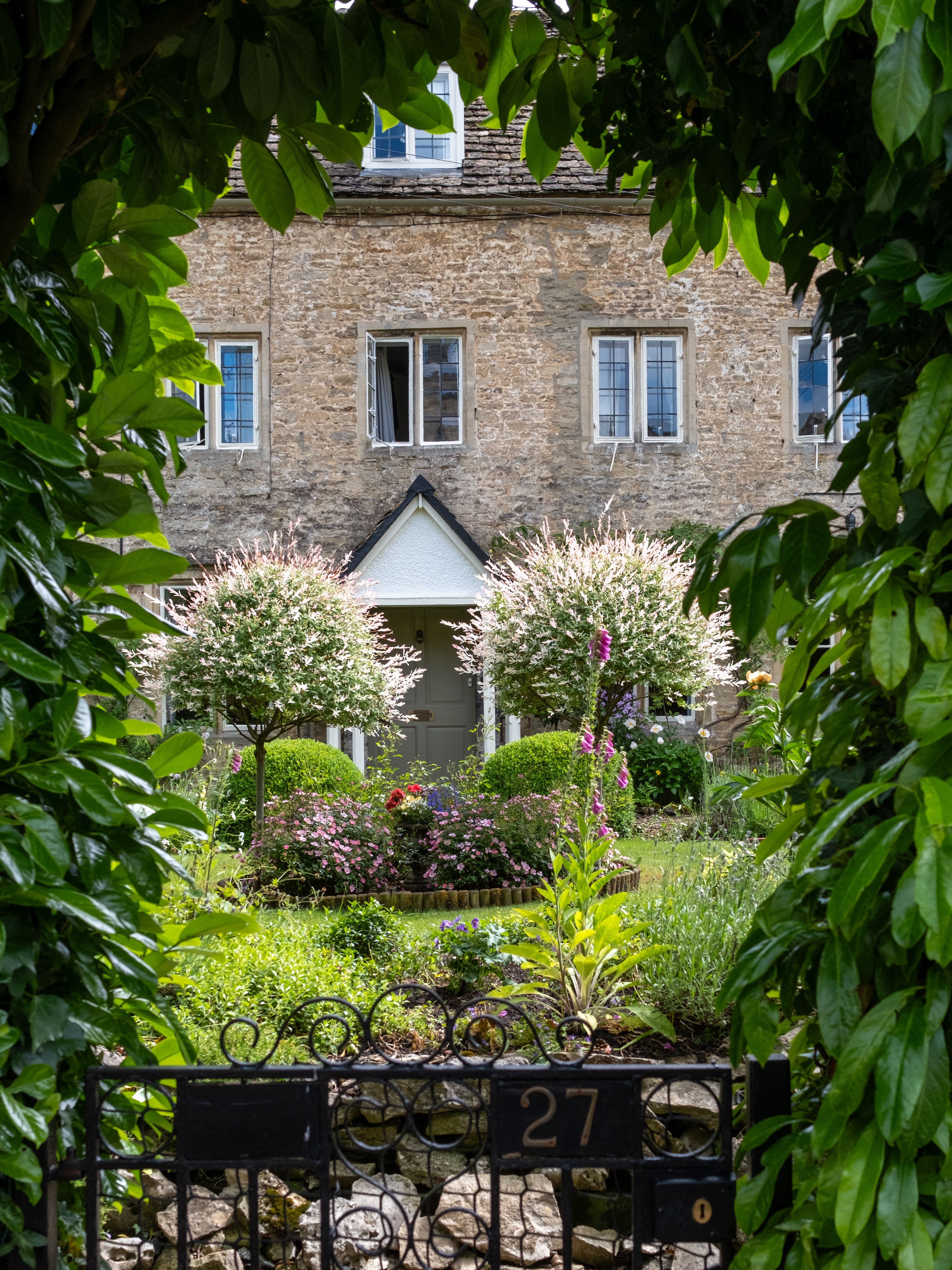 A picturesque view of an English garden framed by lush greenery in Cirencester, UK.