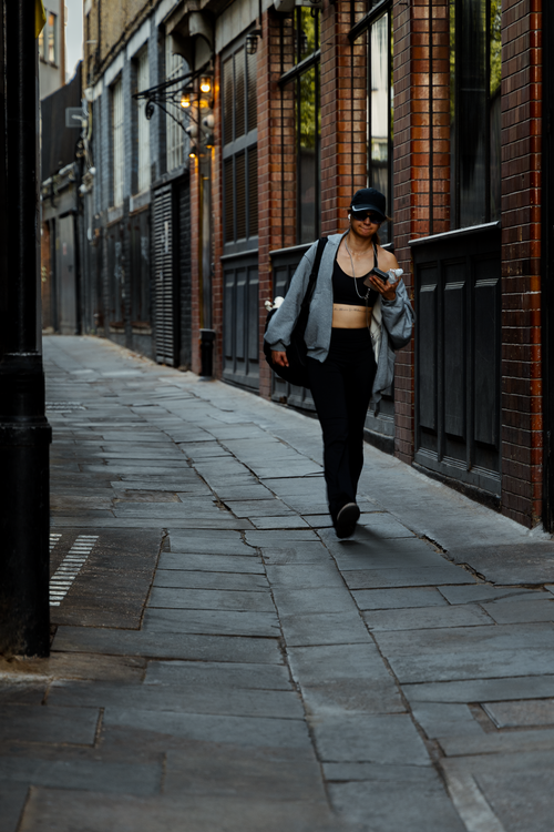 Free Woman confidently walks through a London alley, showcasing urban street style and modern lifestyle. Stock Photo