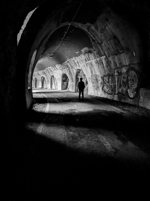 Free Black and white photo of a person in a graffiti-decorated tunnel in Menaggio, Italy. Stock Photo