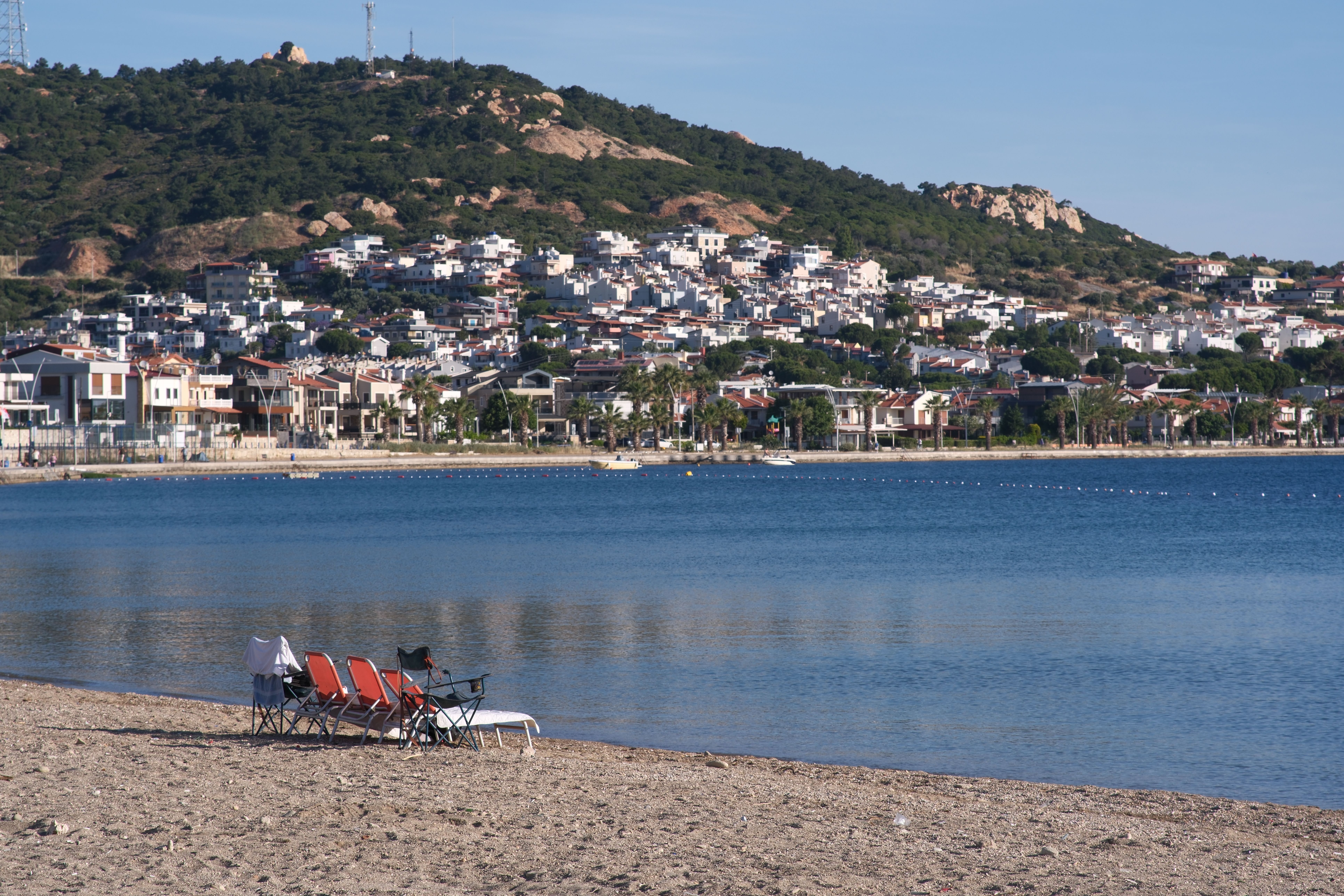 Calm beach scene in Foça, İzmir, Türkiye with rows of homes and serene water. — Trójmiasto