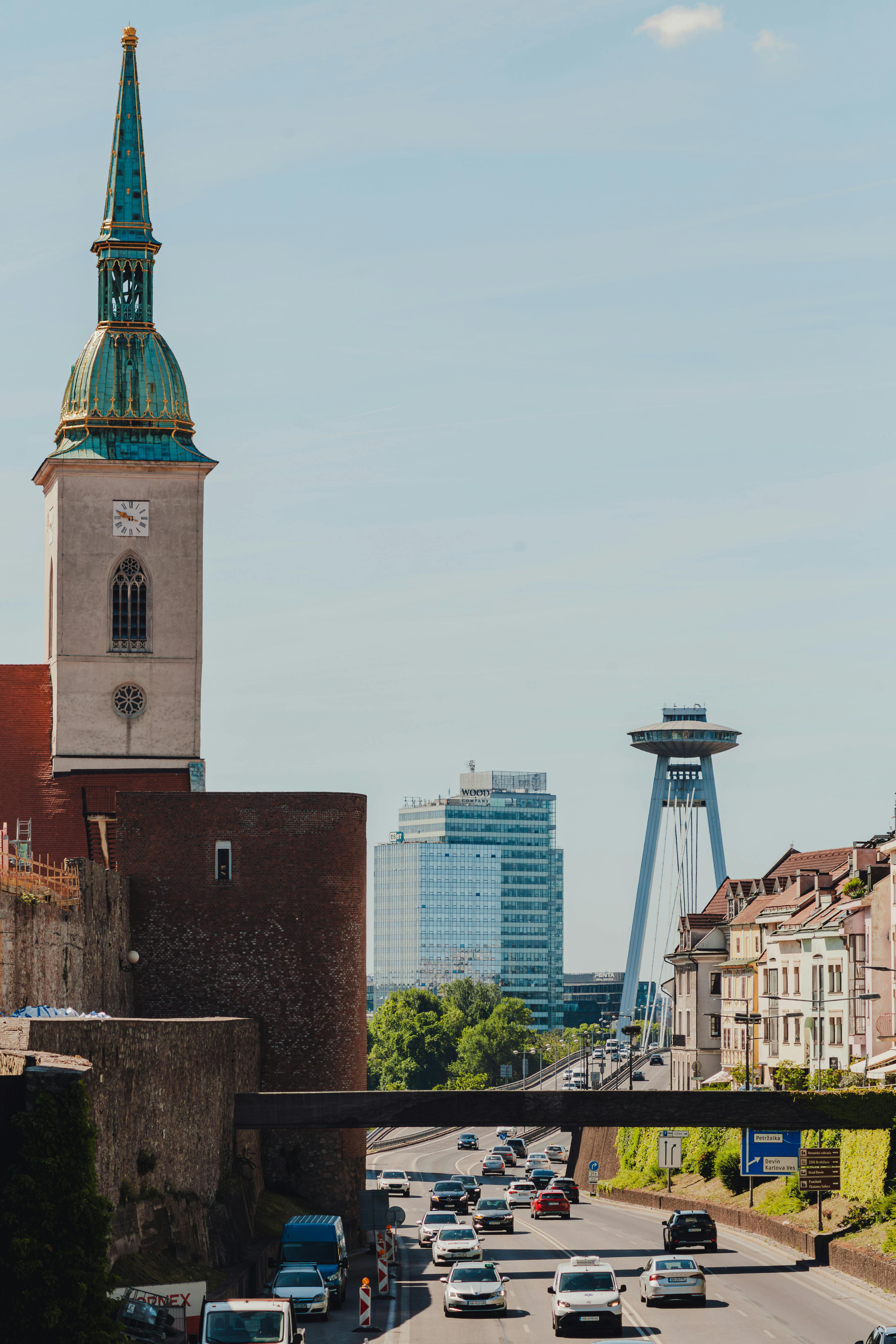 View of Bratislava's skyline featuring St. Martin's Cathedral and the UFO Bridge over a busy road.