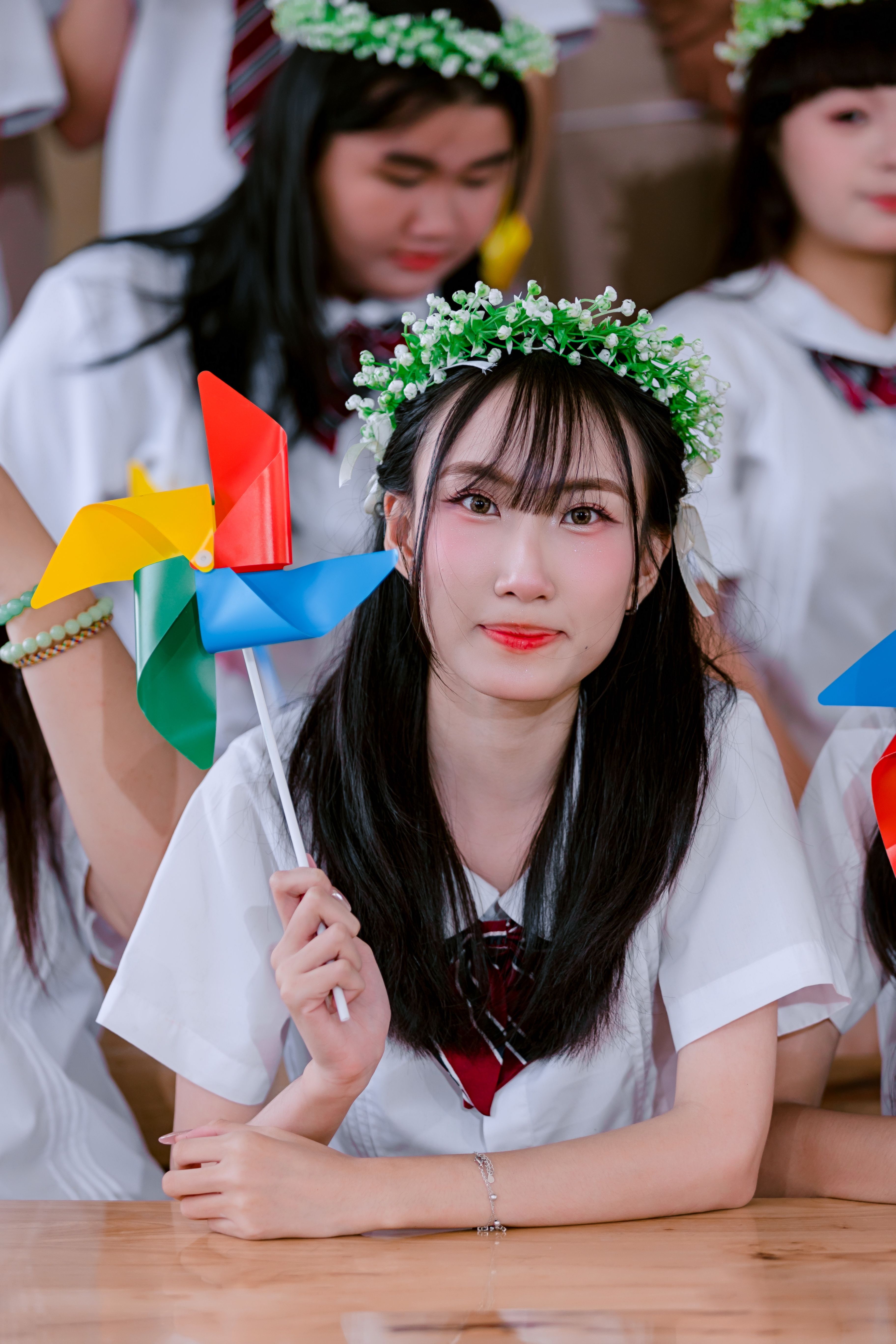 Young woman in a wreath holding a colorful pinwheel, symbolizing celebration.