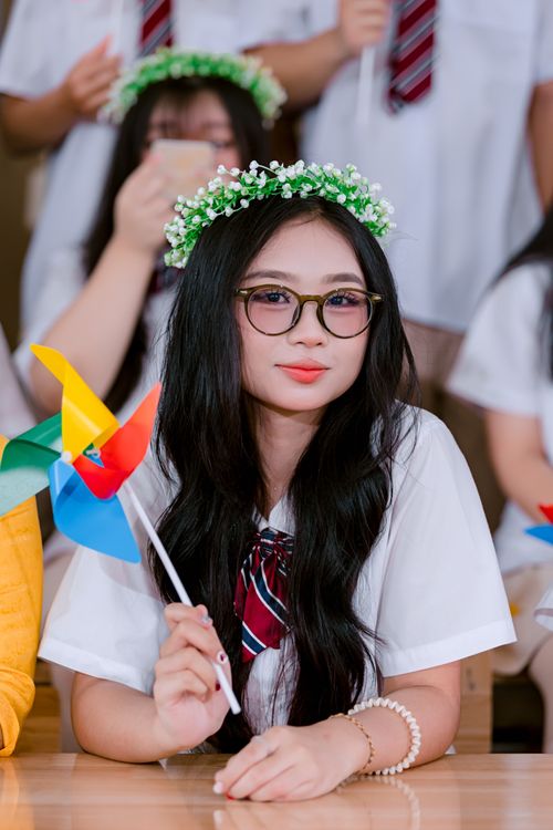 Free Young woman with glasses and flower crown holding a colorful pinwheel indoors. Stock Photo