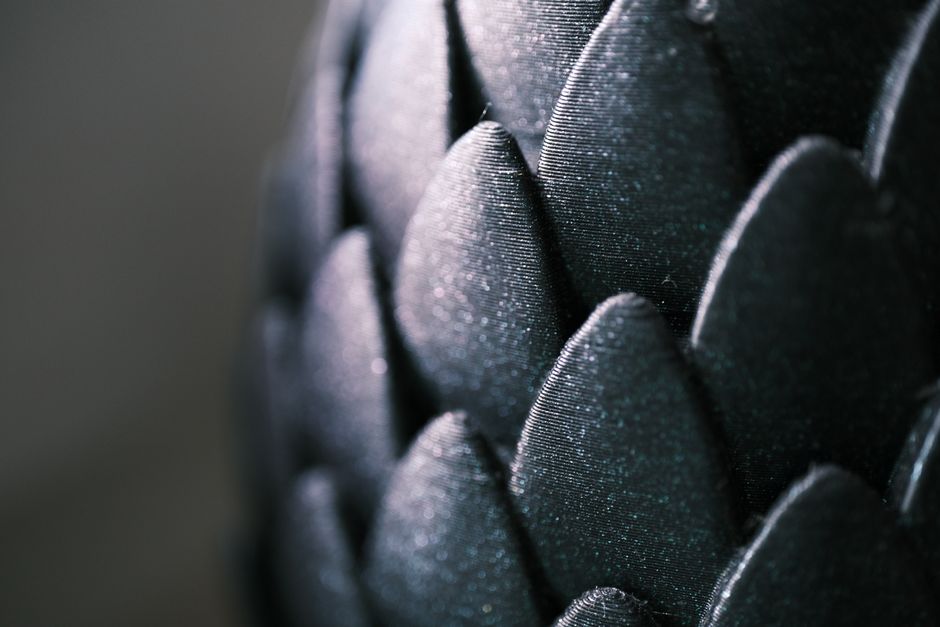 Intricate close-up of glossy black scale-like pattern with a captivating texture and shimmer.