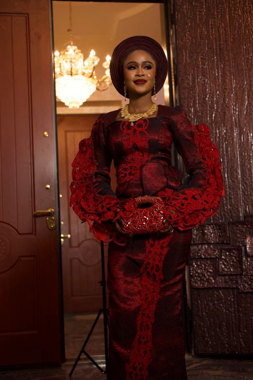 Free Portrait of a Nigerian bride in burgundy lace gown with gold jewelry, embodying West African elegance. Stock Photo