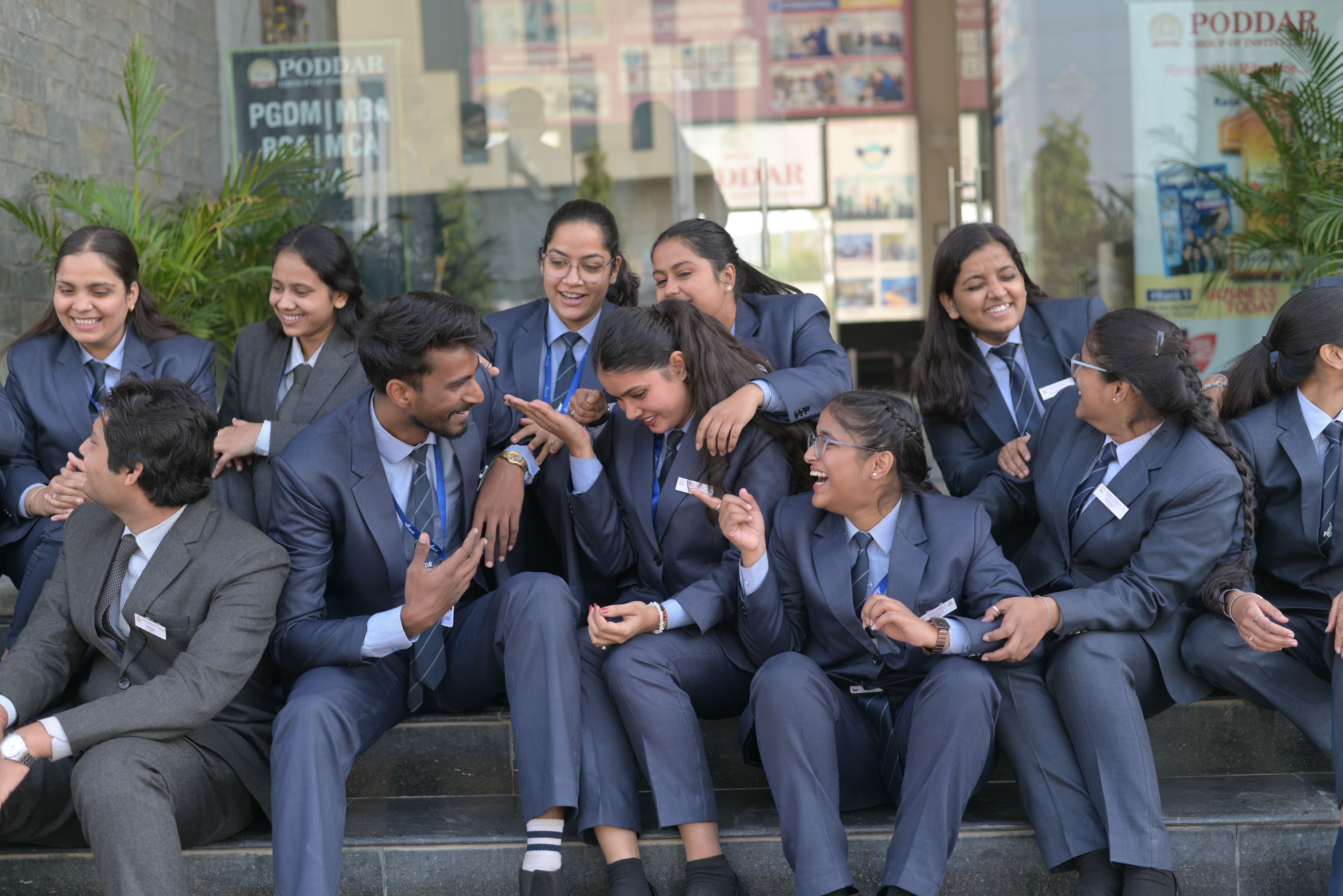Business students in formal attire enjoying a lively conversation outdoors, showcasing teamwork and camaraderie.