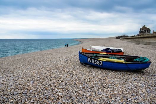 Scenic view of colorful boats on a pebble beach with a vast coastline in the UK.