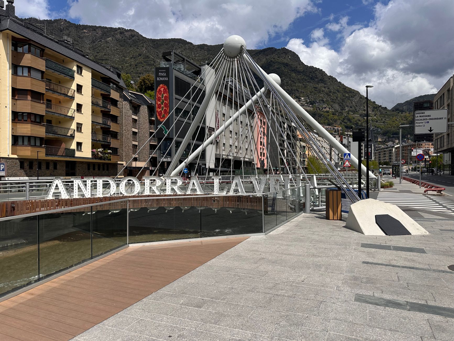 Iconic bridge in Andorra la Vella with mountains and urban architecture under a cloudy sky.. Photo by James Smith on Pexels