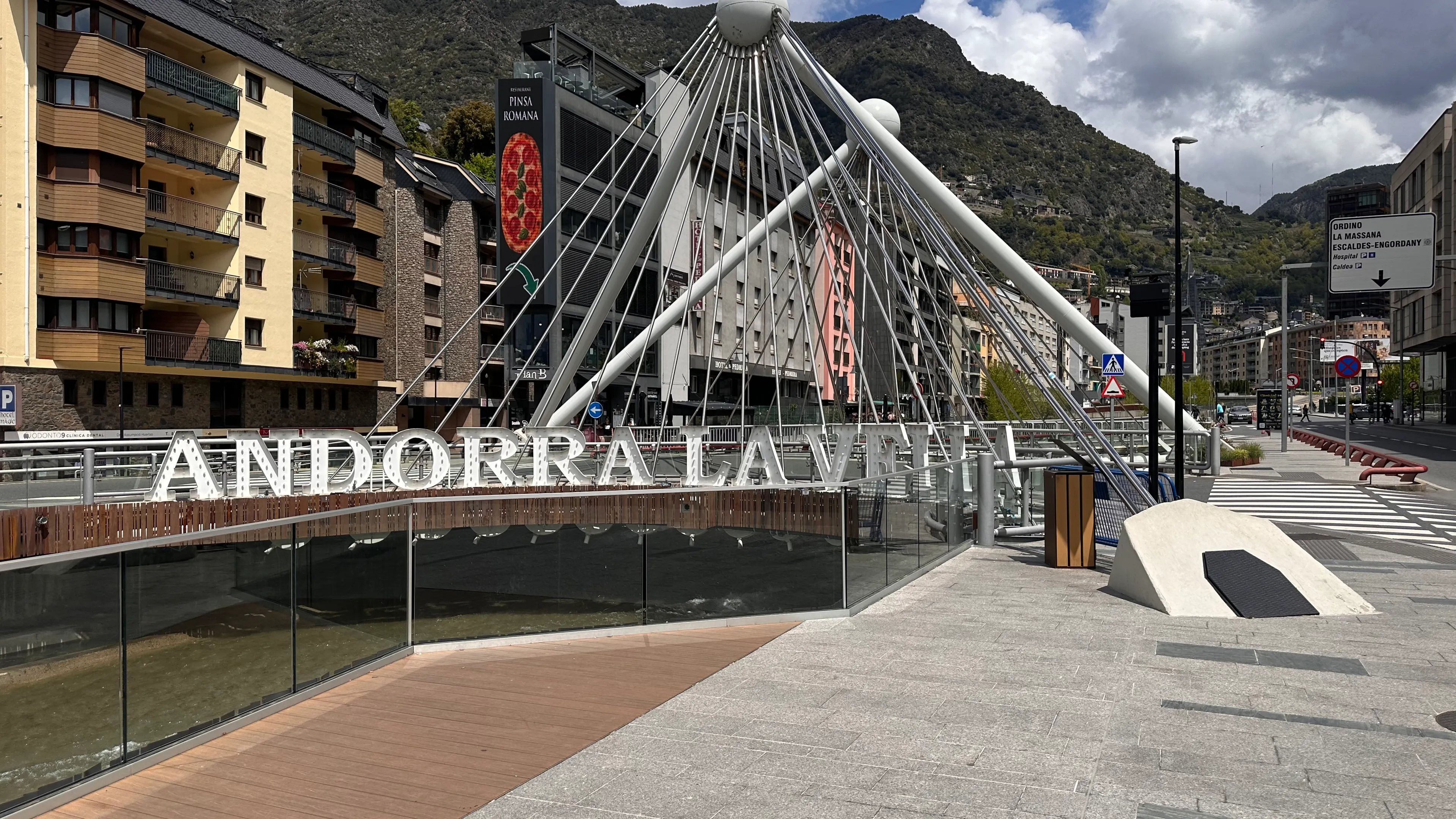 Iconic bridge in Andorra la Vella with mountains and urban architecture under a cloudy sky.