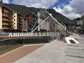 Iconic bridge in Andorra la Vella with mountains and urban architecture under a cloudy sky.