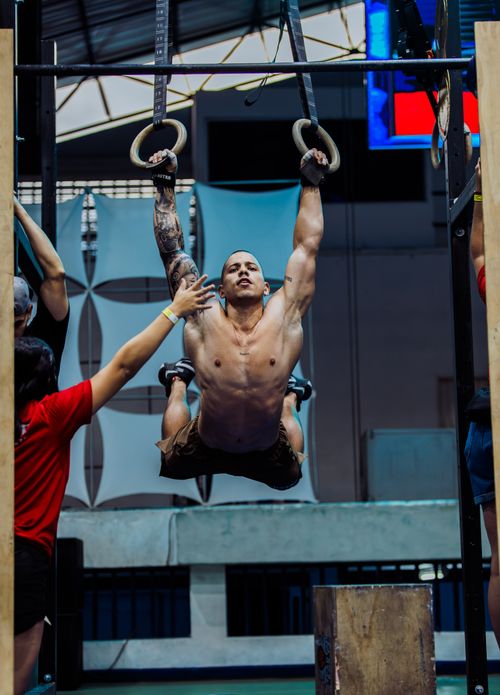Free An athlete executes a muscle-up on gymnastic rings in a gym. Captured indoors at a sports event. Stock Photo
