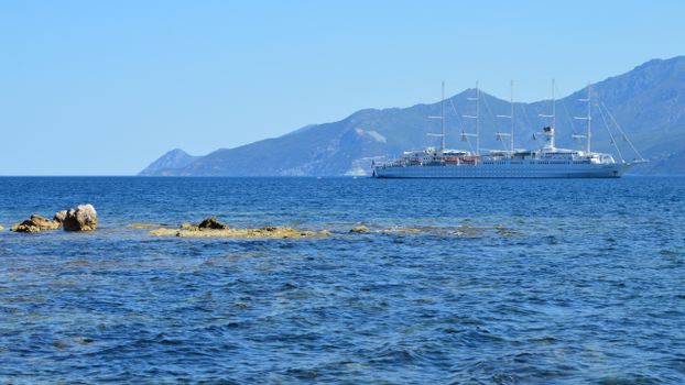 A luxury cruise ship sails against the stunning backdrop of Saint-Florent's coastline in Corsica.