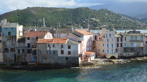 Picturesque view of Saint-Florent's seaside village with colorful buildings and stunning landscape in Corsica, France.