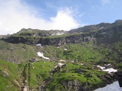 Free Vibrant green mountain landscape with patches of snow under a clear sky in Transylvania, Romania. Stock Photo