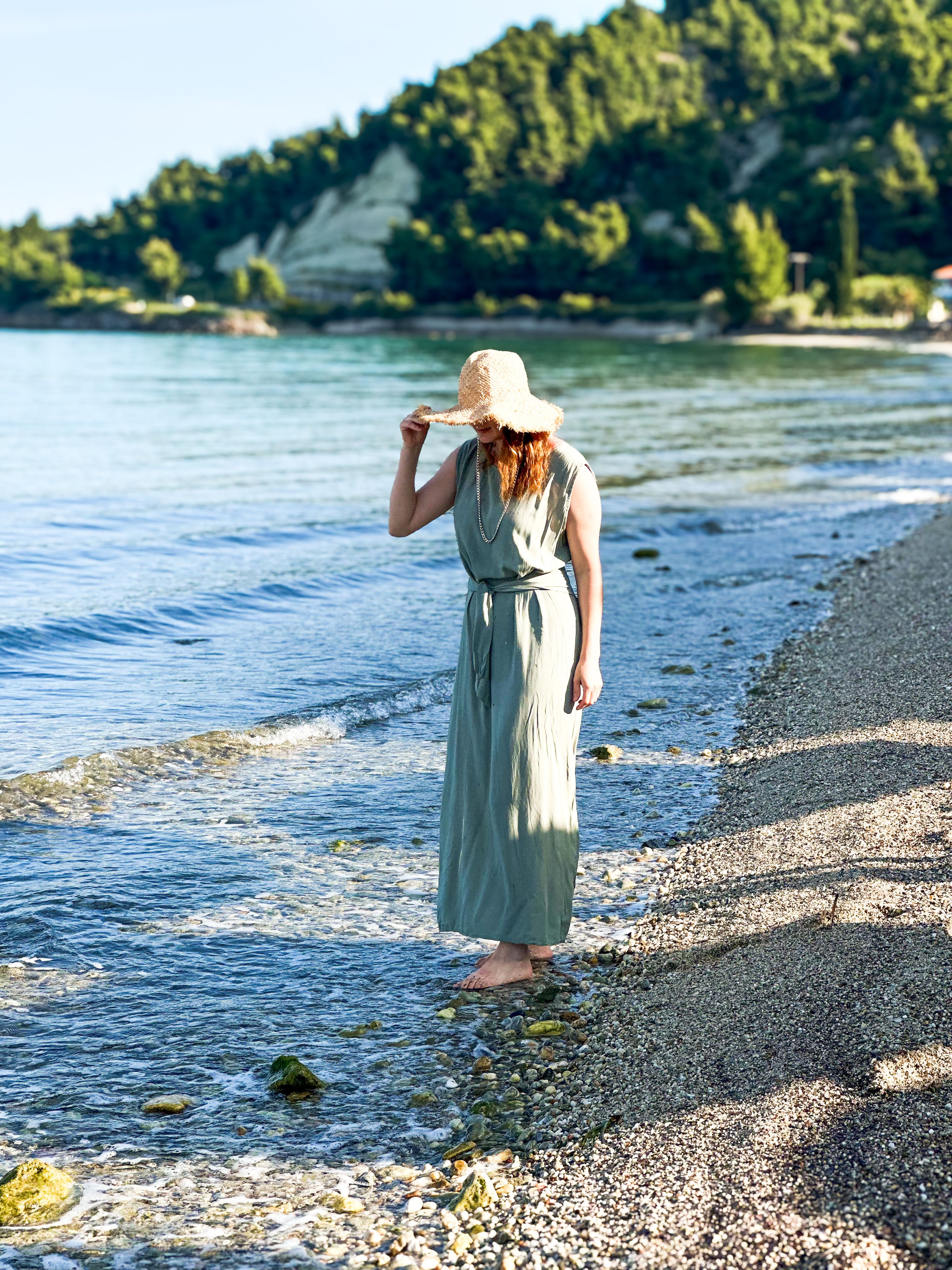 Woman in a summer dress enjoying a peaceful walk along the beach shoreline.