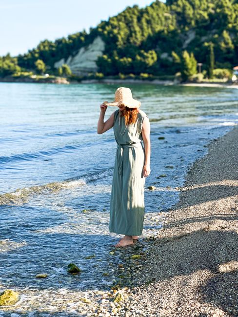 Woman in a summer dress enjoying a peaceful walk along the beach shoreline.