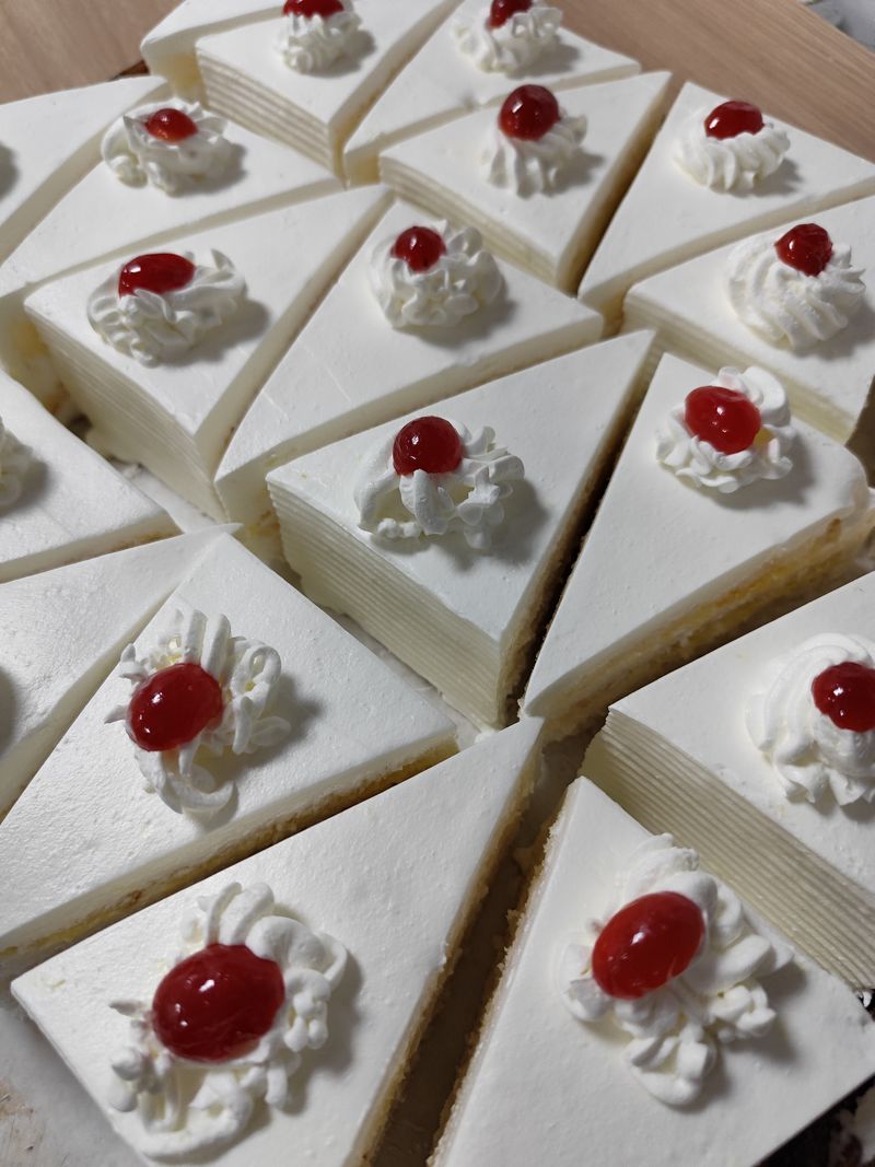 Hausgemachte Kuchenstücke mit Sahne und Kirschen (Stockfoto)